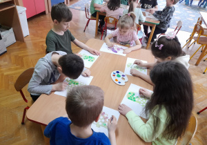 Dzieci stemplują farbami sylwety dinozaurów